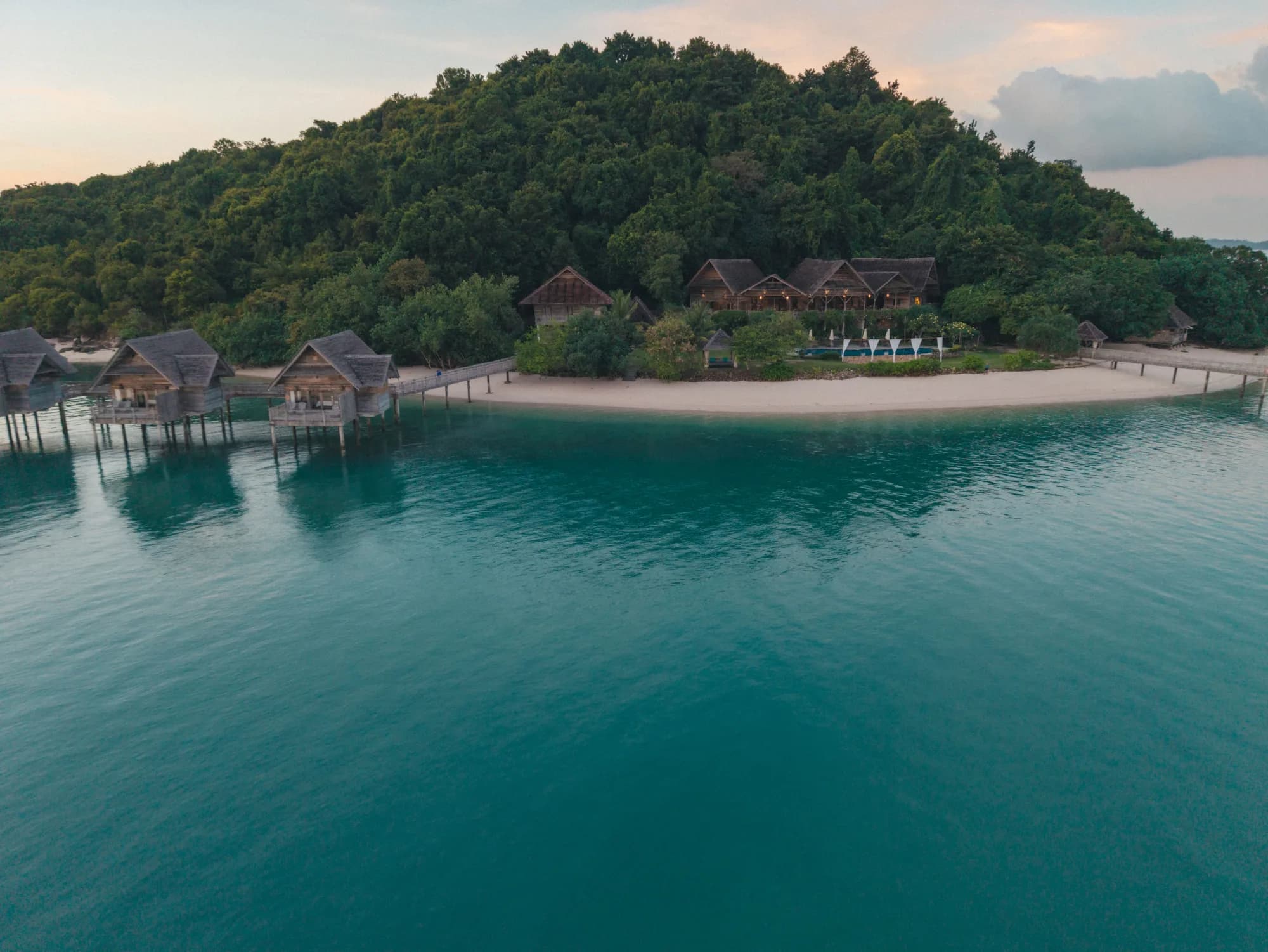 Aerial view of the Grand Lodge and overwater villas at Telunas Private Island, dusk