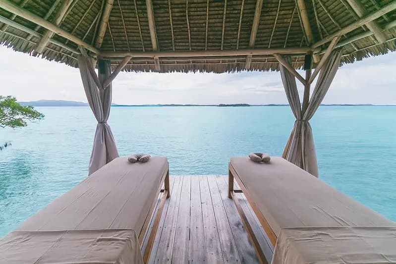 A covered waterfront deck overlooking clear water at Telunas Private Island.