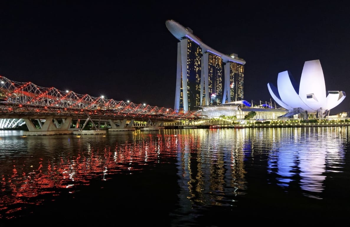 a body of water with a bridge and a lit up building
